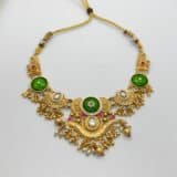 “Gold-plated temple green stone necklace set displayed on jewellery stand with matching earrings – traditional Indian wedding jewellery.”