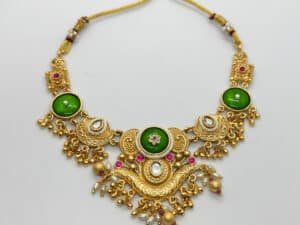 “Gold-plated temple green stone necklace set displayed on jewellery stand with matching earrings – traditional Indian wedding jewellery.”