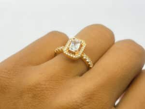 “Gold rectangular-cut American diamond ring on woman’s finger”