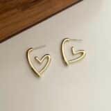 “Gold anti-tarnish heart hoop earrings with glossy finish on white background”